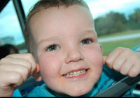 Child smiling, holding his ears